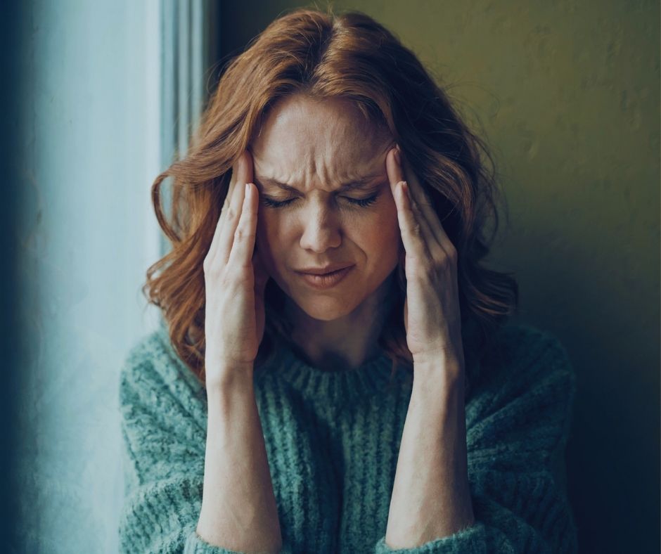 Person resting their hands on their temples during a migraine
